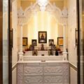 Hand carved white marble pooja mandir for apartment interiors with detailed floral carving